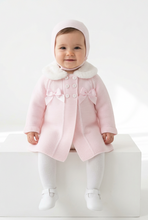 Load image into Gallery viewer, Baby girl wearing the pink coat and bonnet, seated on a white studio block