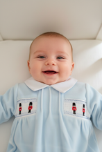 Load image into Gallery viewer, Baby smiling up at camera in blue soldier sleepsuit
