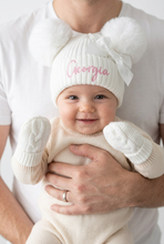 Load image into Gallery viewer, Baby supported upright wearing white pom-pom hat and mittens