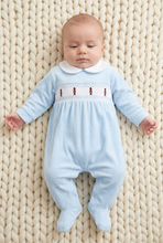 Load image into Gallery viewer, Baby wearing the blue soldier-embroidered sleepsuit on an ivory chunky-knit blanket