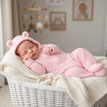 Load image into Gallery viewer, Sleeping newborn in the pink pramsuit curled on a cream blanket in a white basket