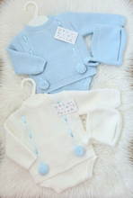 Load image into Gallery viewer, White knitted outfit and matching hat brightened to clean white, preserving the blue details on a large white fluffy rug